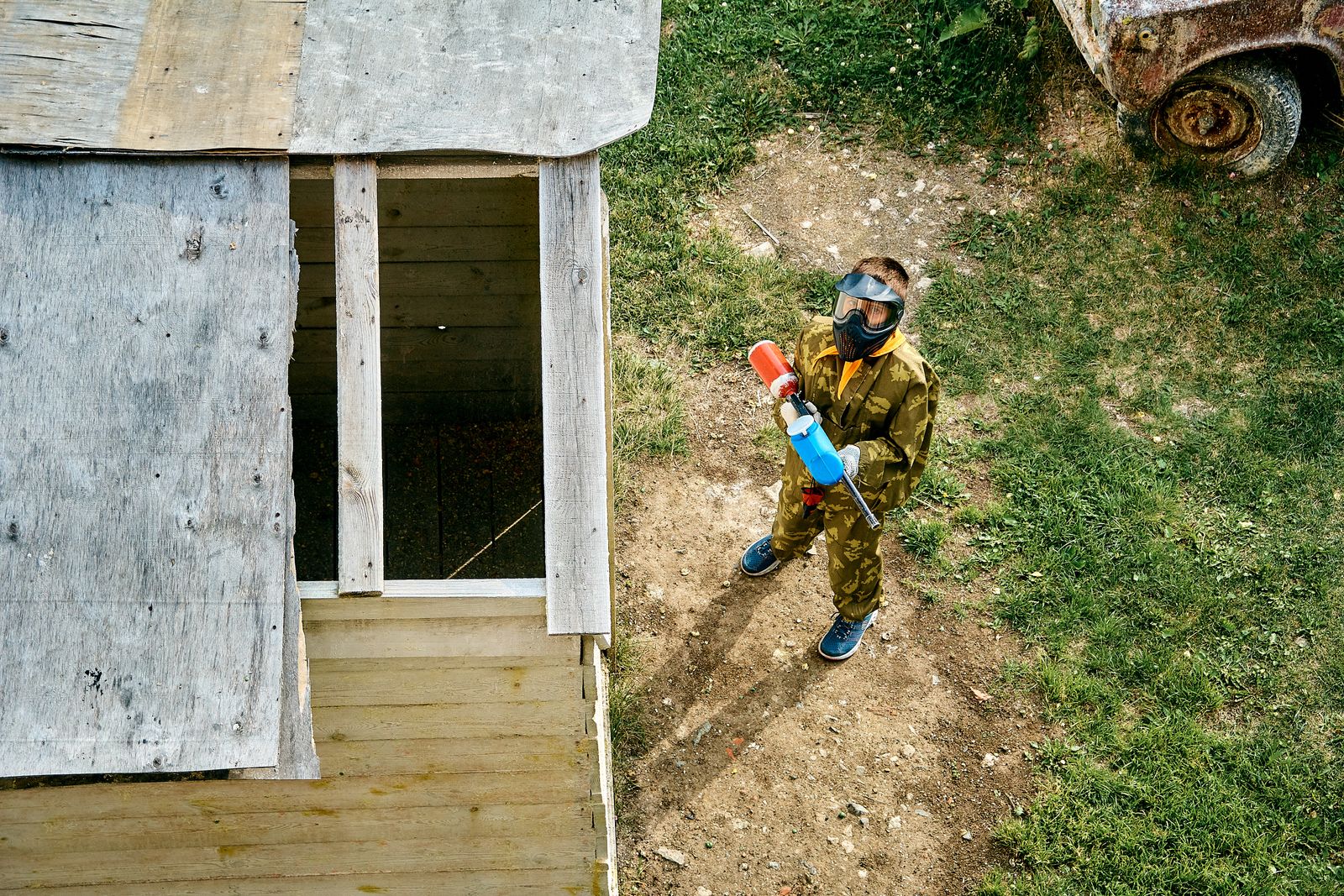 Иж бүрэн хувцастай залуу гадаа paintball тоглож буй дээрээс харсан үзэгдэл